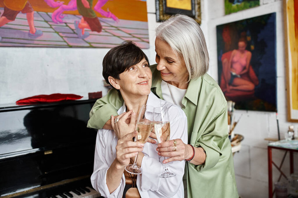 Dwie kobiety dzielą się winem w studio sztuki. - Zdjęcie, obraz