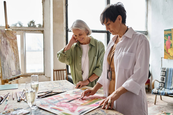 Две пожилые женщины, любующиеся произведениями искусства в художественной студии. - Фото, изображение