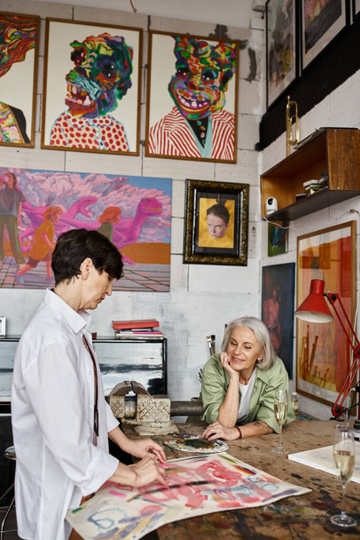 Mature lesbian couple analyzing artwork in studio. - Fotó, kép