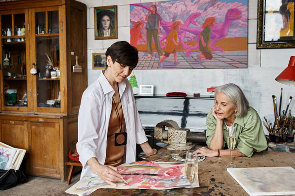 Duas mulheres admiram uma pintura em um estúdio de arte. - Foto, Imagem
