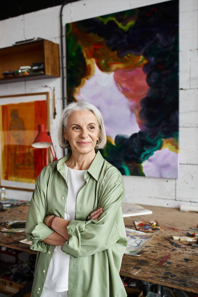 A woman standing before a captivating painting in an art studio. - Photo, Image