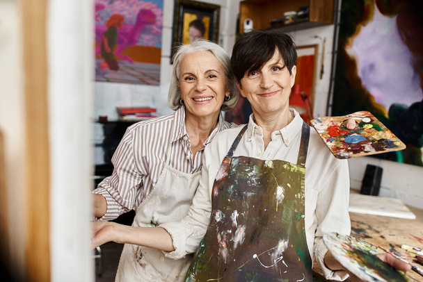 Mature lesbian couple enjoying a creative moment in an art studio. - Zdjęcie, obraz