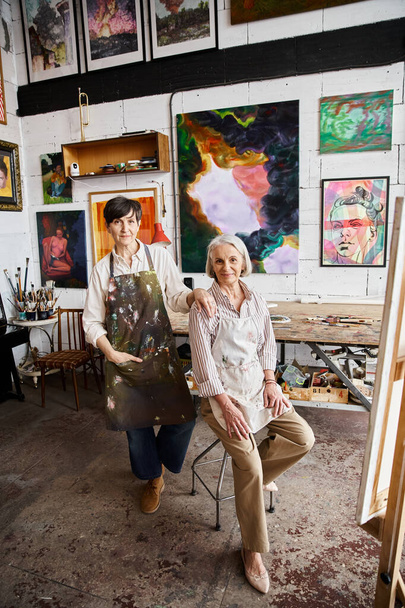 volwassen lesbisch paar bewonderen schilderijen in gezellige kamer. - Foto, afbeelding