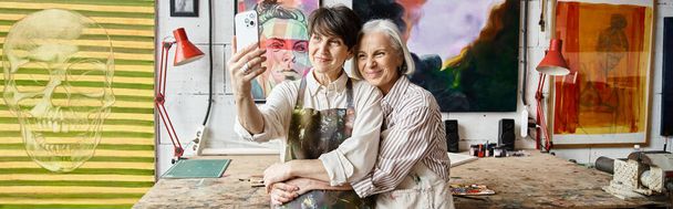 Deux femmes, couple lesbien mature, assise dans un studio d'art. - Photo, image