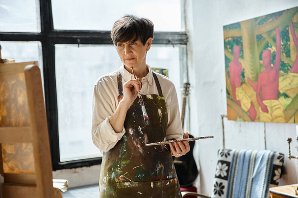 Woman in art studio creating with paintbrush. - Zdjęcie, obraz