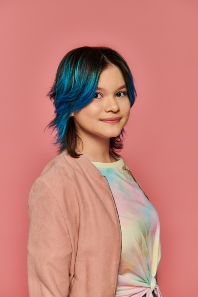 Una ragazza asiatica con i capelli blu in piedi con fiducia davanti a una parete rosa brillante. - Foto, immagini