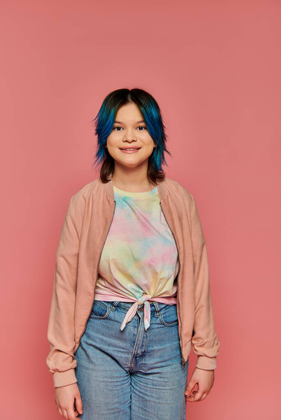 Uma menina com cabelo azul fica confiante na frente de uma parede rosa brilhante. - Foto, Imagem