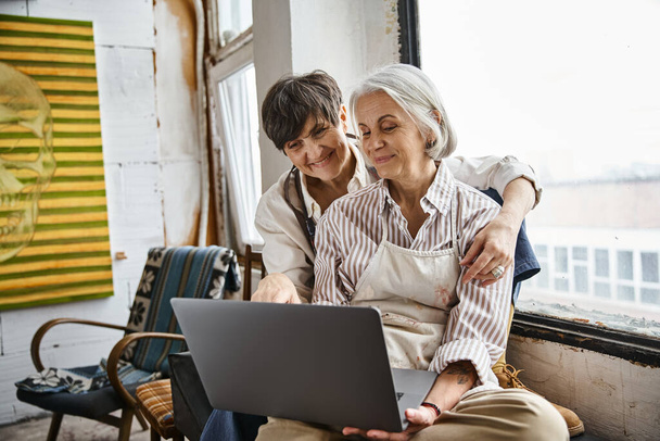 Két nő interakció laptop képernyő hangulatos környezetben. - Fotó, kép