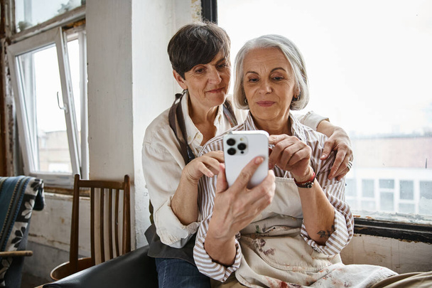 Dos mujeres usando su teléfono para tomar una foto. - Foto, Imagen