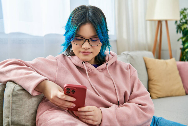 Aasialainen tyttö siniset hiukset istuu tyytyväisesti sohvalla rento kulumista kotona. - Valokuva, kuva