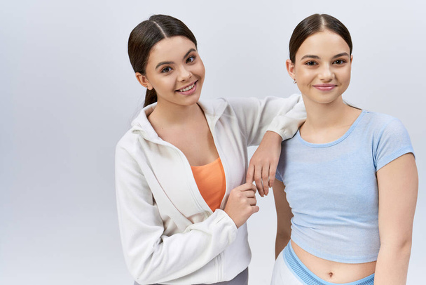 Twee mooie, jonge brunettes in sportkleding die zij aan zij staan en vriendschap en vertrouwen tonen. - Foto, afbeelding