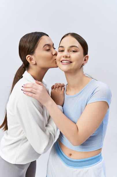 Дві красиві дівчата-підлітки, одна в блакитній сорочці, цілуються один з одним в ніжний момент. - Фото, зображення