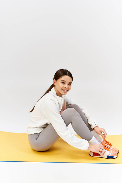Une fille sereine avec les jambes croisées sur le tapis, exprimant calme et stabilité. - Photo, image