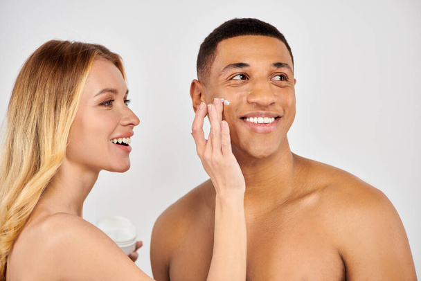 Muž a žena láskyplně aplikovat krém na obličej spolu. - Fotografie, Obrázek
