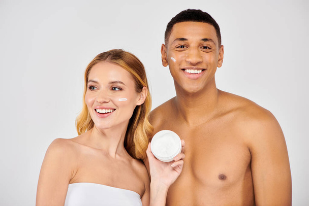 Una pareja disfrutando de un momento de cuidado de la piel con crema facial. - Foto, Imagen