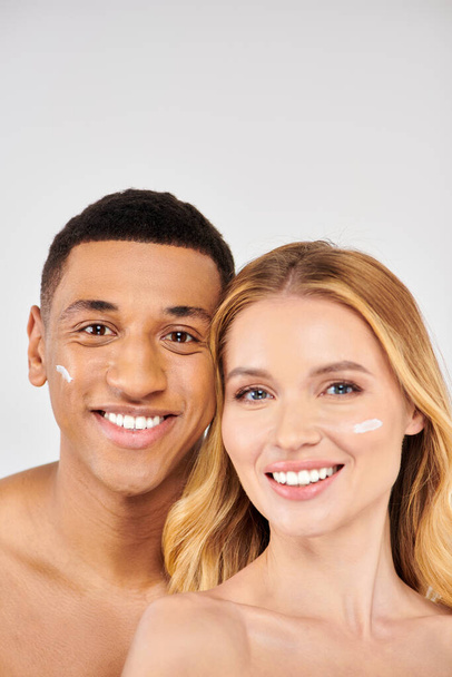Stijlvolle man en vrouw die samen poseren tijdens een huidverzorgingsroutine, crème op het gezicht. - Foto, afbeelding