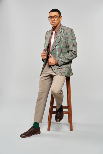 Muž sedí elegantně na stoličce ve stylovém kostkovaném saku. - Fotografie, Obrázek