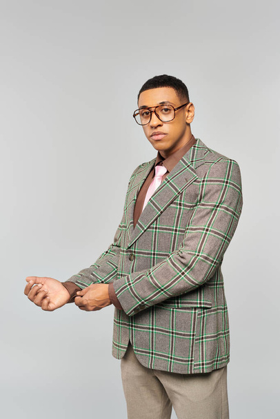 Un hombre con gafas posa con confianza en una elegante chaqueta a cuadros. - Foto, imagen