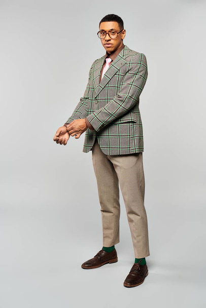 Un homme à la mode dans un blazer à carreaux pose fièrement pour la caméra. - Photo, image