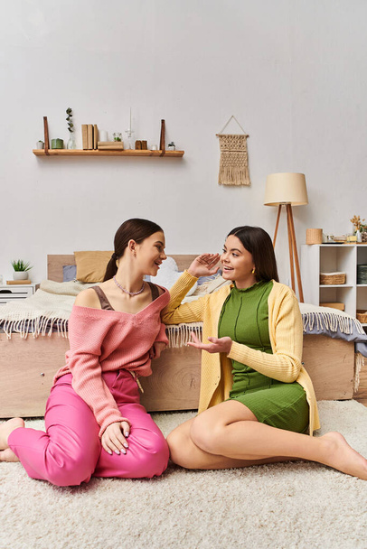 Dvě dospívající dívky v neformálním oblečení sedí na podlaze zabývající se hlubokou konverzaci doma. - Fotografie, Obrázek