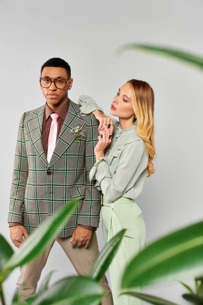 Hombre y mujer posan románticamente frente a una planta verde vibrante. - Foto, imagen