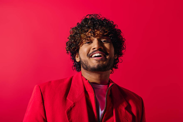 Nahaufnahme eines stilvollen jungen indischen Mannes in einer leuchtend roten Jacke vor einem farbenfrohen Hintergrund. - Foto, Bild