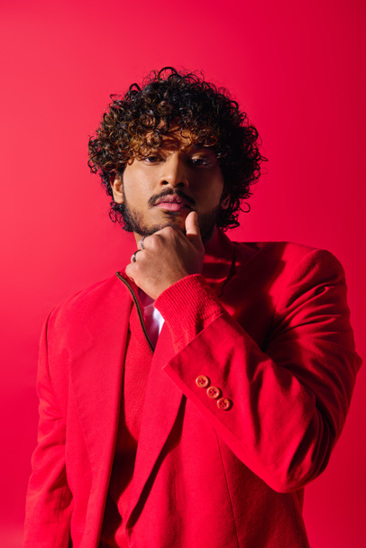 Handsome young Indian man in a striking red suit poses against a vibrant backdrop. - Photo, Image