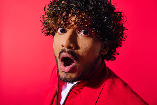Handsome young Indian man with curly hair looks surprised in a vibrant outfit. - Photo, Image
