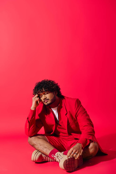 Handsome man in vibrant red suit sitting gracefully on the ground. - Photo, Image