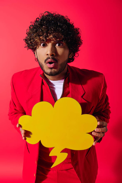 Stylish young man in red suit holding bright yellow speech bubble. - Photo, Image