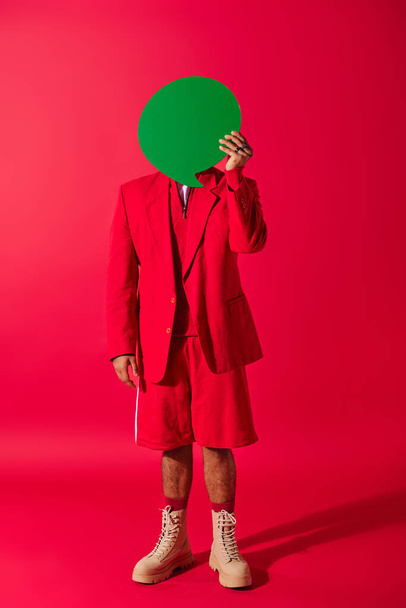 Красивый индийский мужчина в красном костюме держит зеленый пузырь речи над головой на ярком фоне. - Фото, изображение