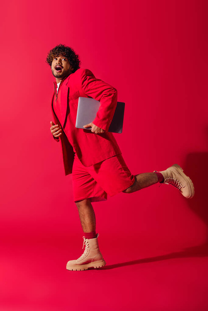 A handsome young Indian man in a vibrant red suit working on a laptop. - Photo, Image