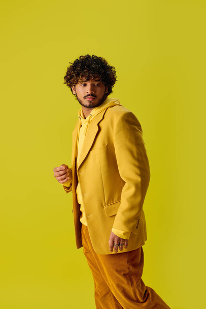 Handsome young Indian man in a vibrant yellow suit strikes a pose against a vivid yellow backdrop. - Photo, Image
