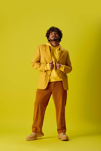 Handsome young Indian man poses in vibrant outfit against vivid yellow backdrop. - Photo, Image