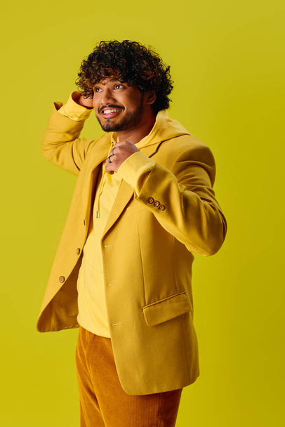Sarı ceketli ve kahverengi pantolonlu yakışıklı Hintli canlı arkaplanda poz veriyor.. - Fotoğraf, Görsel
