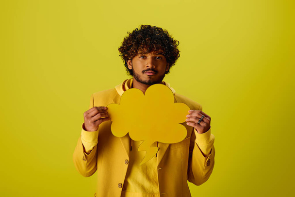 Guapo joven indio con un traje amarillo sosteniendo una burbuja del habla. - Foto, Imagen