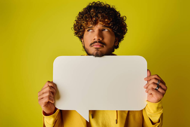 A man with curly hair holding a white speech bubble. - Photo, Image