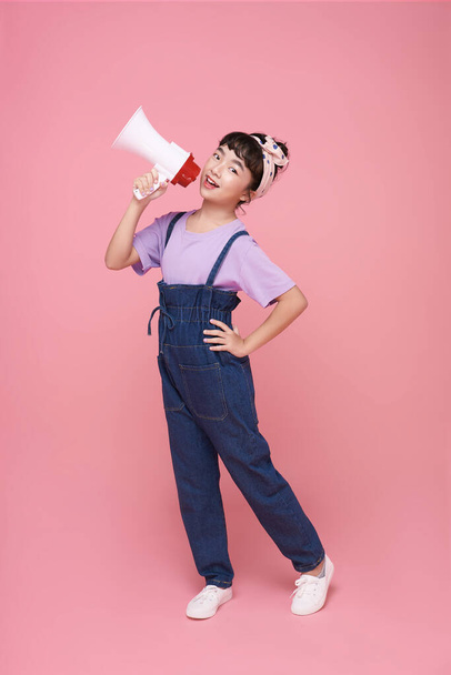 Asian little girl standing and holding megaphone isolated on pink background, Speech and announce concept - Photo, Image