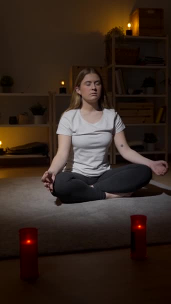 Egy fiatal nő otthon meditál a padlón ülve. Tini lélegzik mélyen lótuszban pózol. - Felvétel, videó