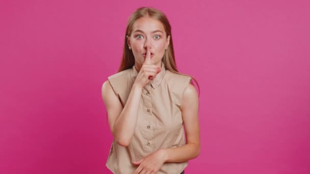 Shh be quiet please. Young woman presses index finger to lips makes silence gesture sign do not tells secret, stop gossip. Pretty attractive blonde girl isolated alone on pink studio background - Footage, Video