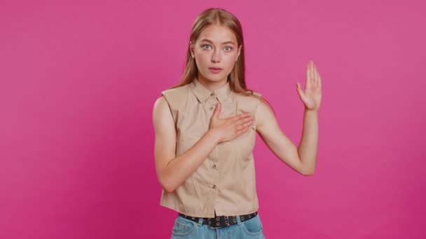 I swear to be honest. Sincere responsible young woman raising hand to take oath, promising to be honest and to tell truth, keeping hand on chest. Girl isolated on pink studio background. Lifestyles - Footage, Video