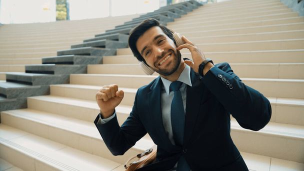 Closeup image of professional business man enjoy to listen music by using headphone. Portrait of skilled project manager show facial expression about joy and happy while sitting at mall. Exultant. - Photo, Image