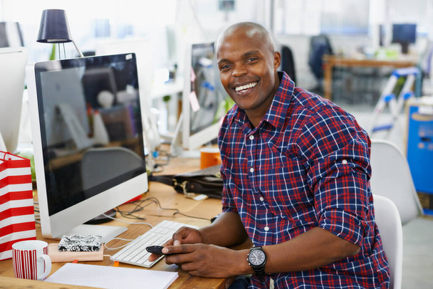 African man, portrait and phone or happy with creative job, technology with web designer in office workspace at desk. Businessman, smile and workplace for online search with internet browse. - Photo, Image