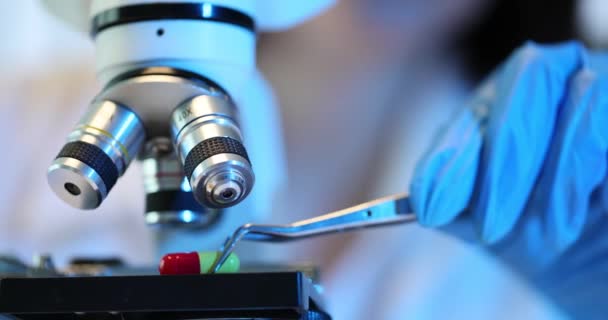 Punaisen keltaisen kapselin mikroskooppinen analyysi mikroskoopilla. Lääkkeiden kehittäminen laboratoriossa - Materiaali, video