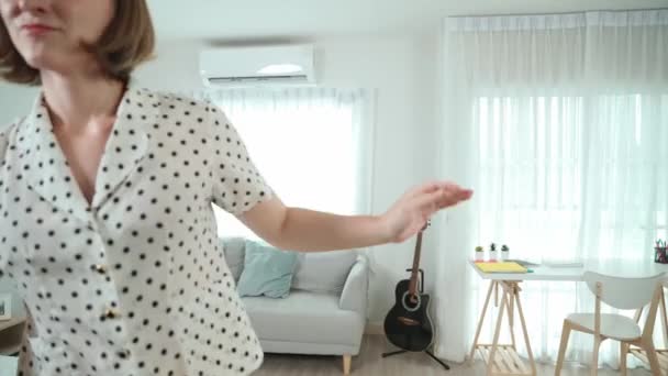 Fehér házvezetőnő felmossa a padlót, miközben élénk hangulatban táncol a modern lakásban. Boldog energikus anya vagy tisztább élvezze a takarítás a nappaliban, miközben a zene. Életstílus. Pedagógia. - Felvétel, videó