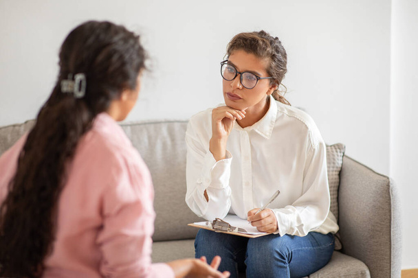 Поддерживающая молодая психотерапевт слушает, как клиентка делится своей историей, мыслями. Концепция психических расстройств - Фото, изображение