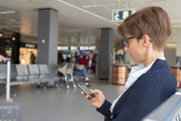 Telefon kullanarak Havaalanı terminalinde bekliyor - Fotoğraf, Görsel
