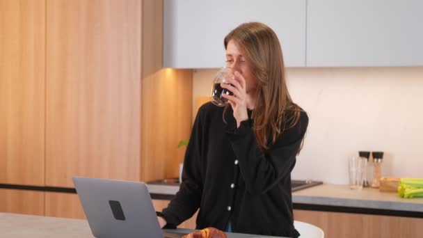 Fiatal kaukázusi nő dolgozik otthonról laptop és ivás csésze kávét. - Felvétel, videó
