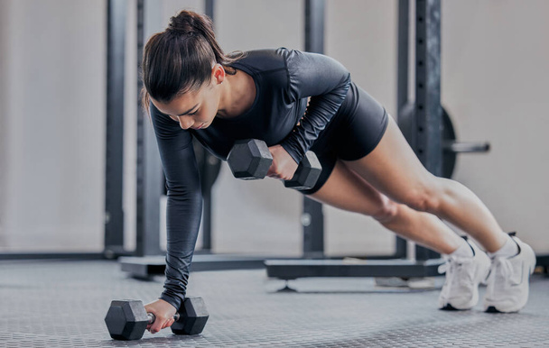 Woman, push up and dumbbell in gym for workout, exercise and training for strong abs or muscle. Female person, bodybuilder and athlete for sport and plank, power core and equipment for weightlifting. - Photo, Image