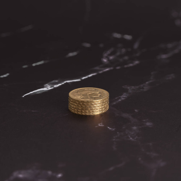 Νεκρή ζωή. Κοντινή στοίβα με χρυσά νομίσματα Louis σε ασπρόμαυρη μαρμάρινη επιφάνεια - Φωτογραφία, εικόνα